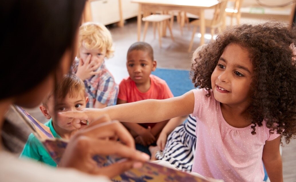 A teacher reads a book to a group of young children.