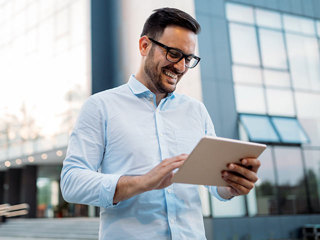 White male on tablet outside in front of building