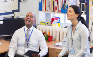 One male and one female school administrator laughing in an office
