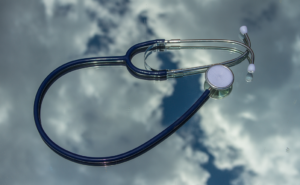 Photo of a stethoscope lying against an image of a cloudy sky