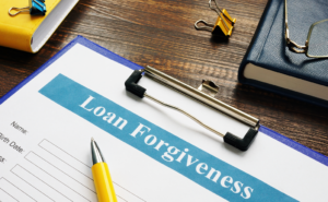 Photo of a clipboard holding a form titled "Loan Forgiveness," across which is laying a yellow pen