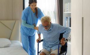 Female nurse helps a elderly while male patient out of a chair
