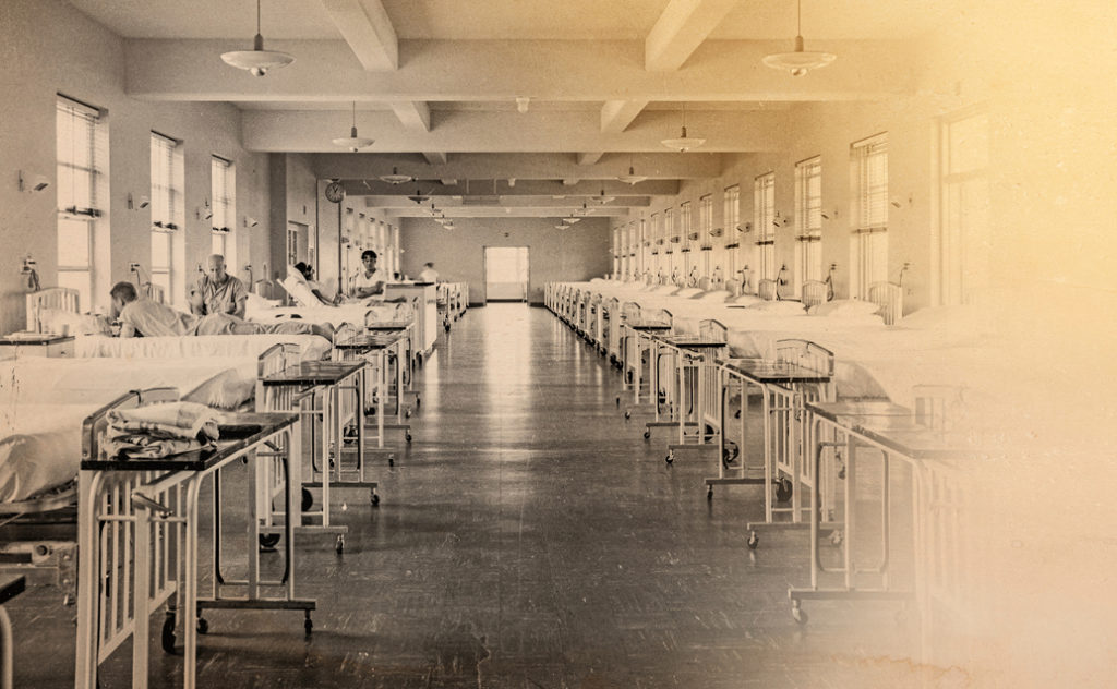 Old sepia-toned photograph of a corridor lined with hospital cots