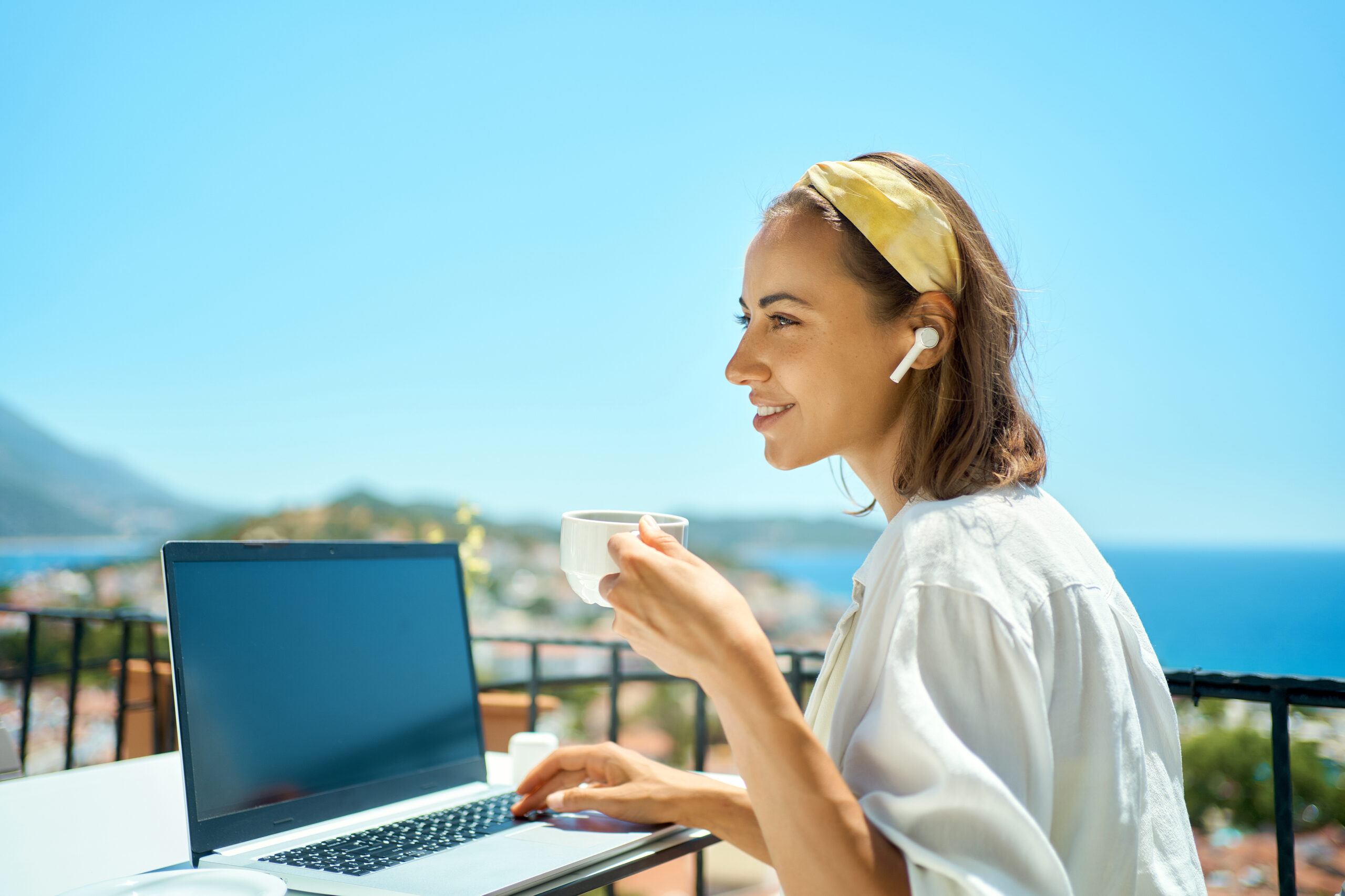 Young business woman drinking coffee and working on laptop computer at sea resort