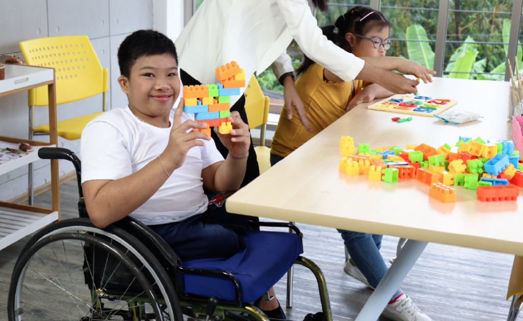 Image of a male student in a wheelchair sitting at a desk in an inclusive classroom