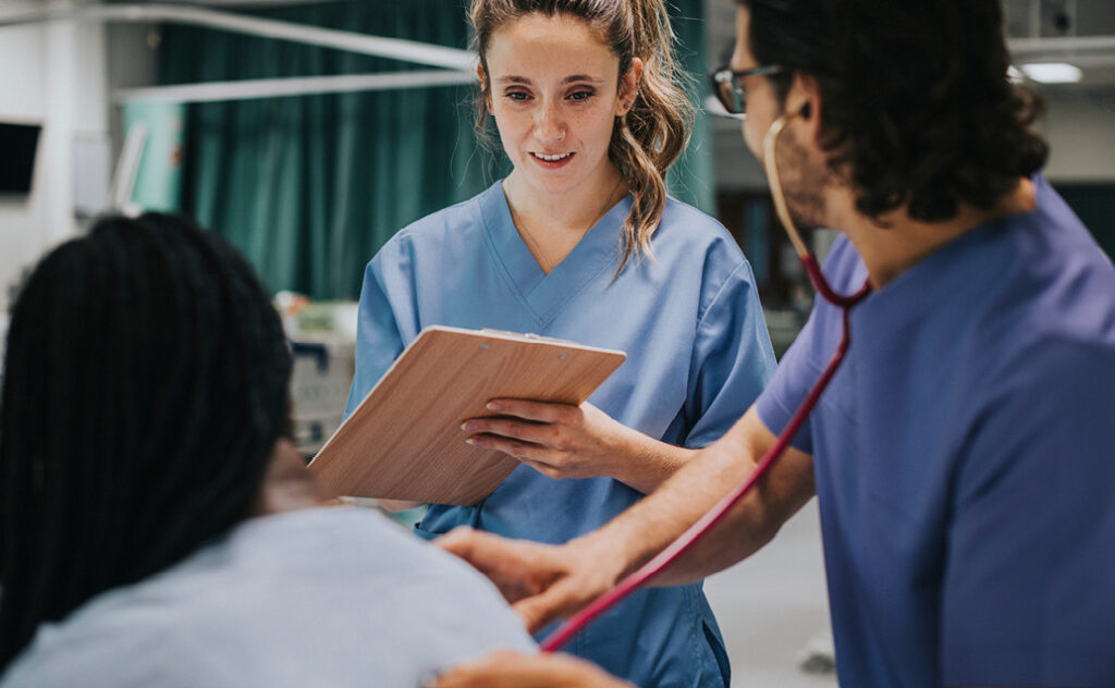 Image of a new nurse observing an experienced nurse helping a patient