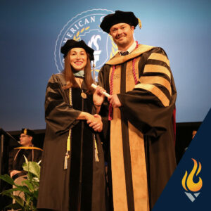Picture of two people standing on a stage exchanging a degree