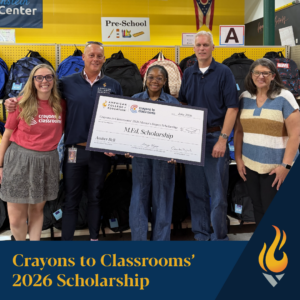 Five people pose in a classroom holding a large scholarship check for Amber Bell