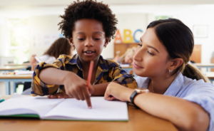 Teacher helping a student write in a classroom