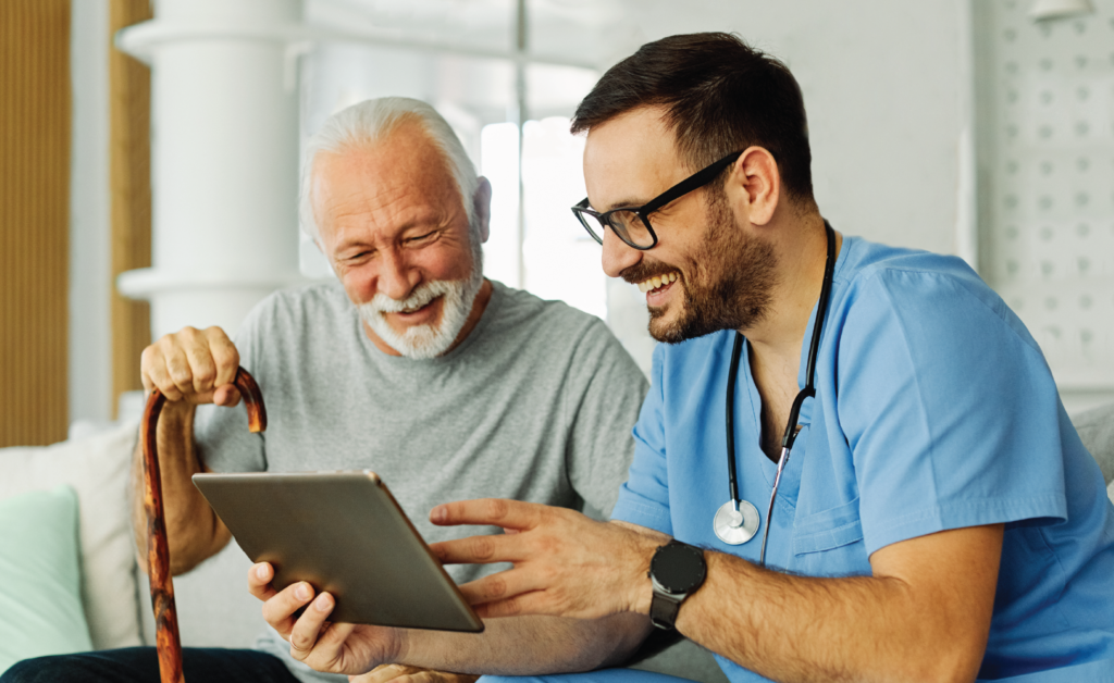 Doctor showing a tablet to a smiling elderly man in a hospital room