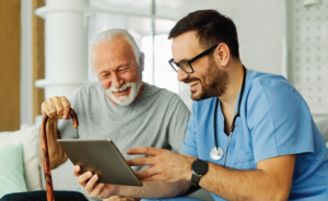 Doctor showing a tablet to a smiling elderly man in a hospital room