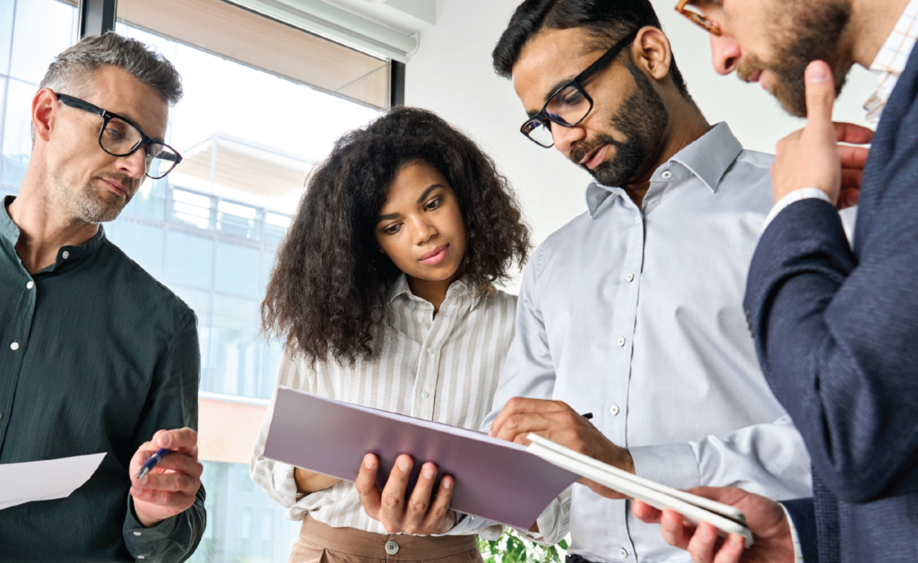 Group of business professionals reviewing a document together during an office meeting.