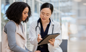 Doctor in a white coat explains information on a tablet to a patient.
